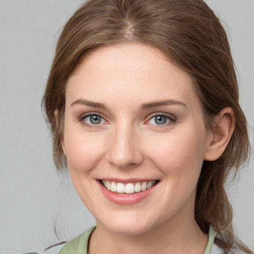 Joyful white young-adult female with medium  brown hair and grey eyes