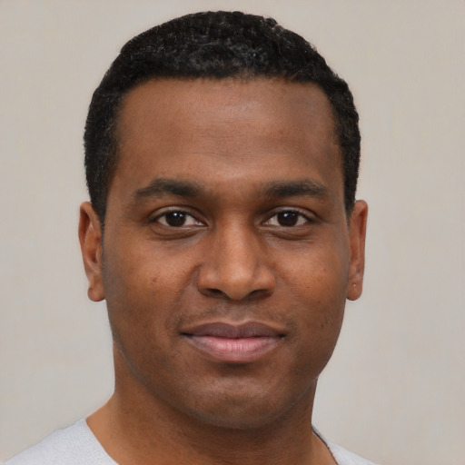 Joyful black young-adult male with short  black hair and brown eyes