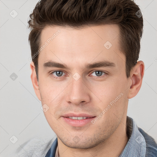 Joyful white young-adult male with short  brown hair and grey eyes