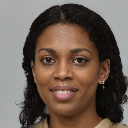 Joyful black young-adult female with long  black hair and brown eyes