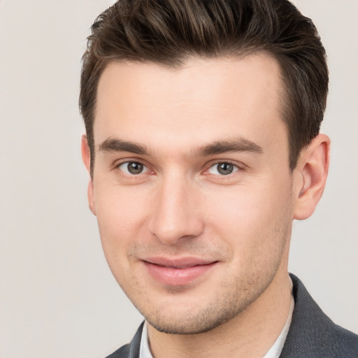 Joyful white young-adult male with short  brown hair and grey eyes