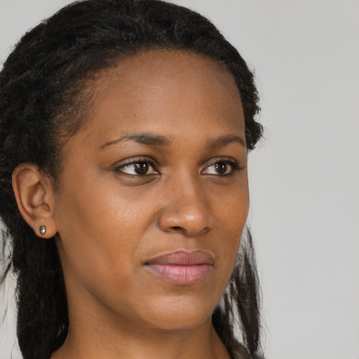Joyful black young-adult female with long  brown hair and brown eyes