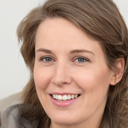 Joyful white adult female with long  brown hair and grey eyes