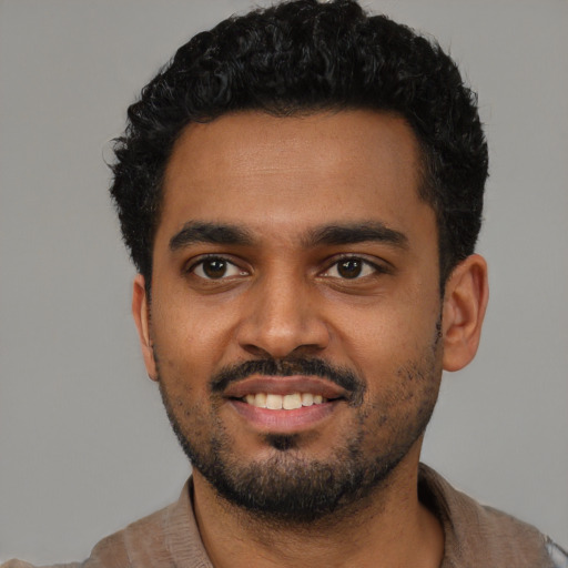 Joyful black young-adult male with short  black hair and brown eyes