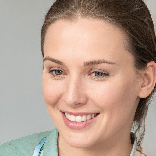 Joyful white young-adult female with medium  brown hair and grey eyes