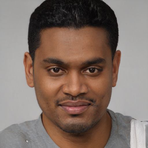Joyful black young-adult male with short  black hair and brown eyes