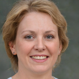 Joyful white adult female with medium  brown hair and blue eyes