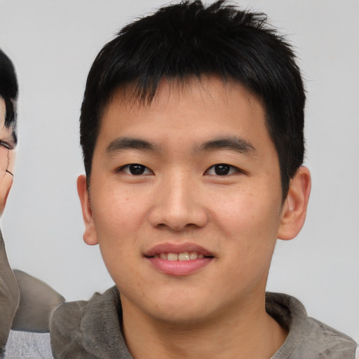 Joyful asian young-adult male with short  black hair and brown eyes