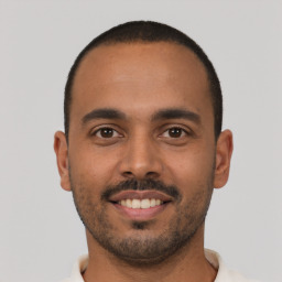 Joyful latino young-adult male with short  black hair and brown eyes