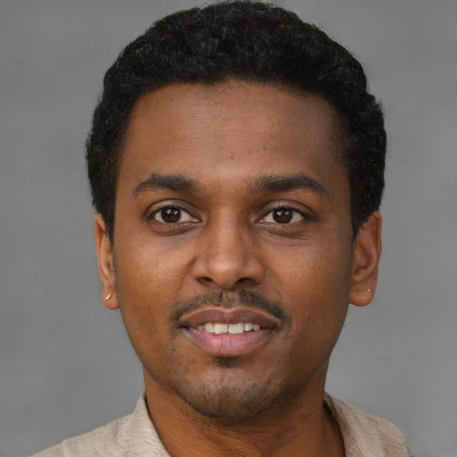 Joyful black young-adult male with short  black hair and brown eyes