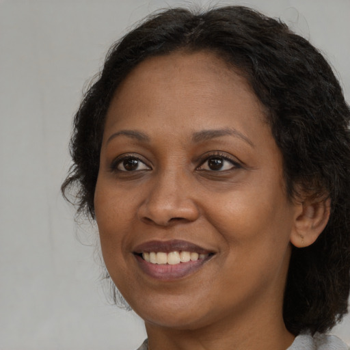 Joyful black adult female with long  brown hair and brown eyes