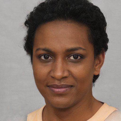 Joyful black young-adult female with short  brown hair and brown eyes