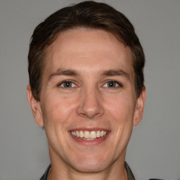 Joyful white adult male with short  brown hair and grey eyes