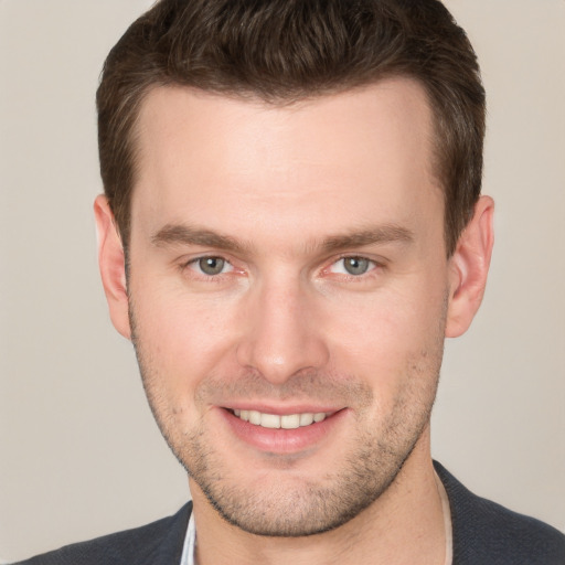 Joyful white young-adult male with short  brown hair and grey eyes