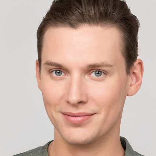 Joyful white young-adult male with short  brown hair and grey eyes