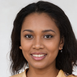 Joyful black young-adult female with long  brown hair and brown eyes