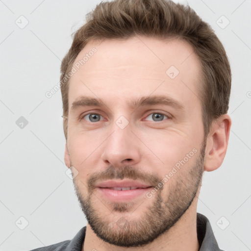 Joyful white young-adult male with short  brown hair and grey eyes