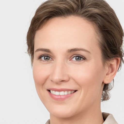 Joyful white young-adult female with medium  brown hair and grey eyes