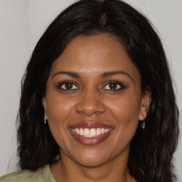 Joyful black young-adult female with long  brown hair and brown eyes