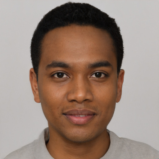 Joyful black young-adult male with short  black hair and brown eyes