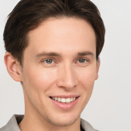 Joyful white young-adult male with short  brown hair and grey eyes