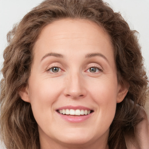 Joyful white adult female with long  brown hair and green eyes