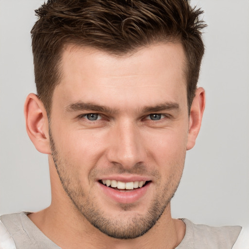 Joyful white young-adult male with short  brown hair and grey eyes