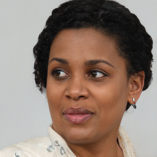 Joyful black young-adult female with short  black hair and brown eyes
