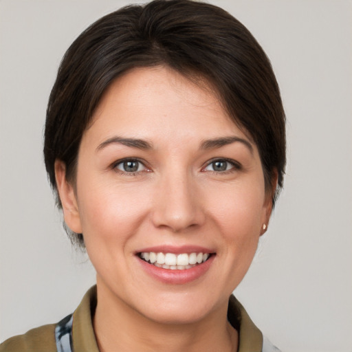 Joyful white young-adult female with medium  brown hair and grey eyes