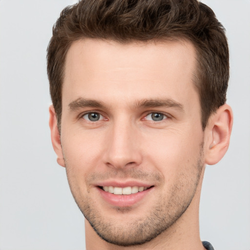 Joyful white young-adult male with short  brown hair and grey eyes