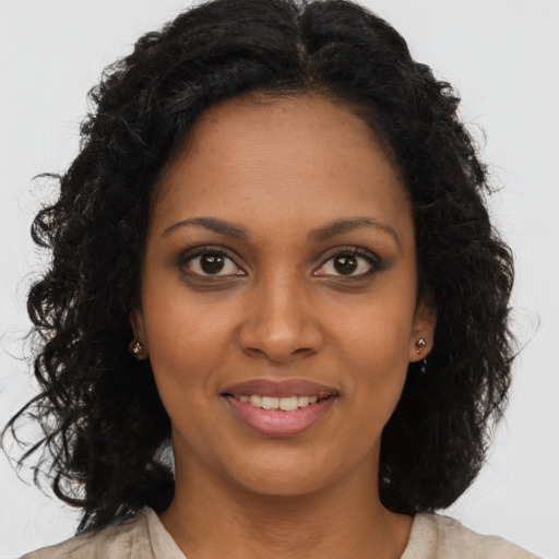 Joyful black young-adult female with long  brown hair and brown eyes