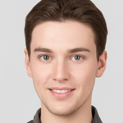 Joyful white young-adult male with short  brown hair and grey eyes