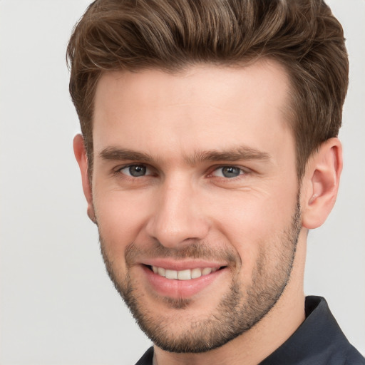 Joyful white young-adult male with short  brown hair and grey eyes