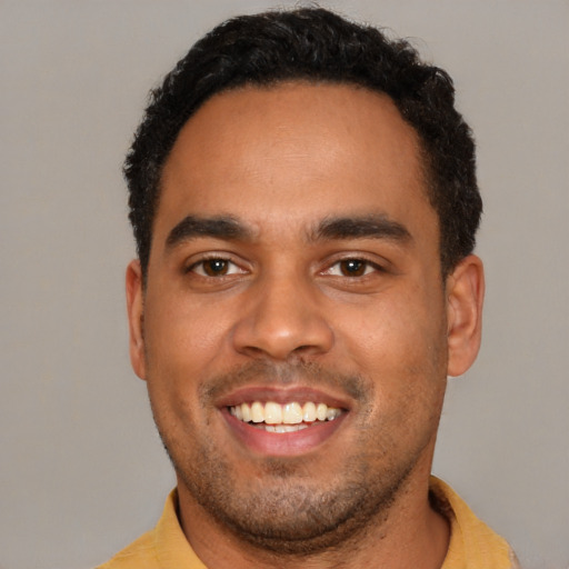 Joyful black young-adult male with short  black hair and brown eyes