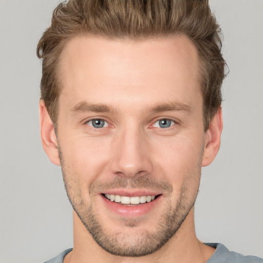 Joyful white young-adult male with short  brown hair and grey eyes