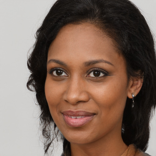 Joyful black adult female with long  brown hair and brown eyes