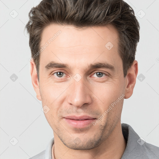 Joyful white young-adult male with short  brown hair and grey eyes