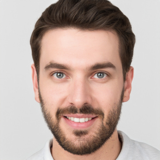 Joyful white young-adult male with short  brown hair and grey eyes