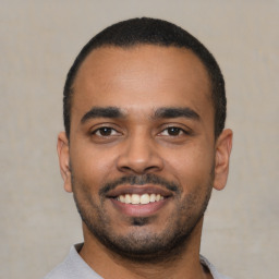 Joyful latino young-adult male with short  black hair and brown eyes