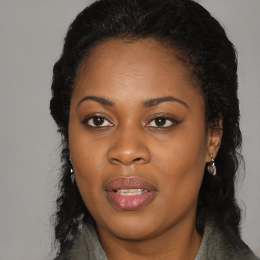 Joyful black young-adult female with long  black hair and brown eyes