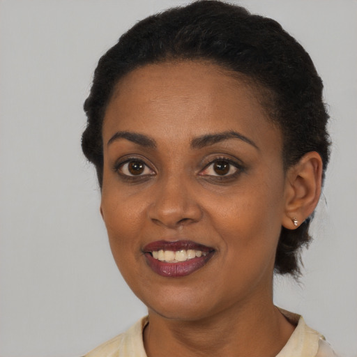 Joyful black young-adult female with short  black hair and brown eyes