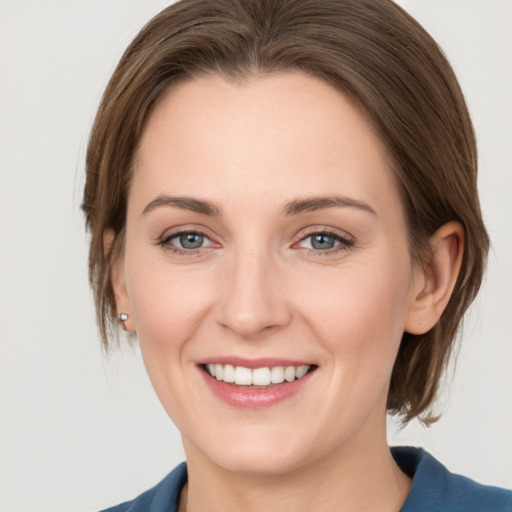 Joyful white young-adult female with medium  brown hair and grey eyes