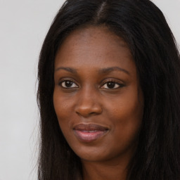 Joyful black young-adult female with long  brown hair and brown eyes