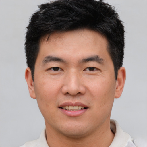 Joyful asian young-adult male with short  black hair and brown eyes