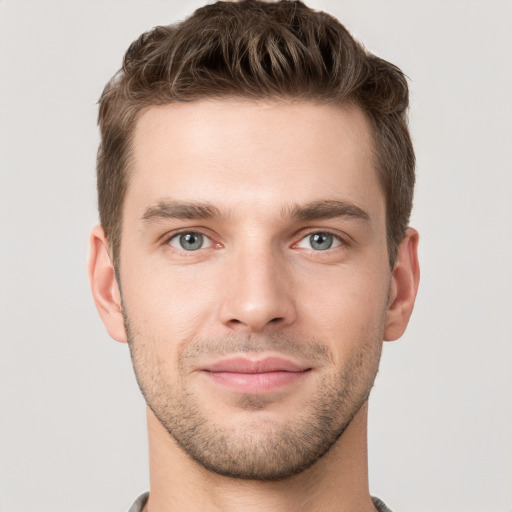 Joyful white young-adult male with short  brown hair and grey eyes