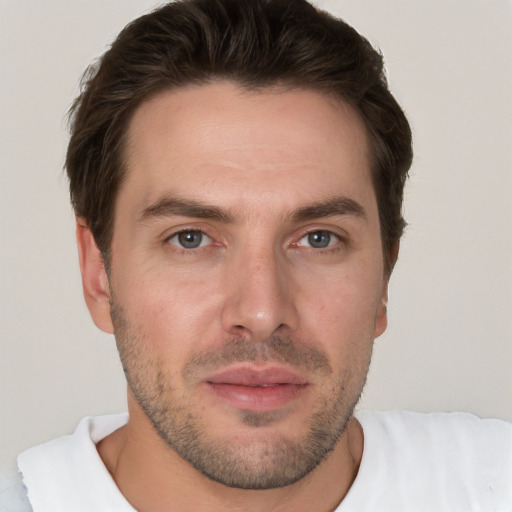 Joyful white young-adult male with short  brown hair and grey eyes