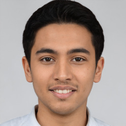 Joyful latino young-adult male with short  black hair and brown eyes