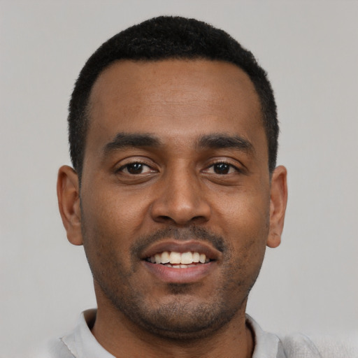 Joyful black young-adult male with short  black hair and brown eyes