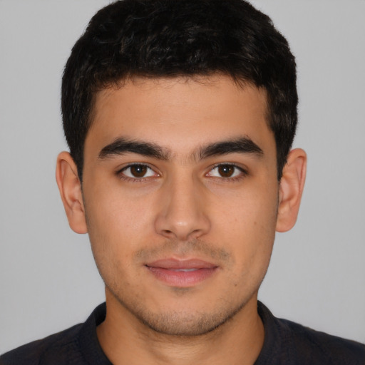 Joyful latino young-adult male with short  brown hair and brown eyes