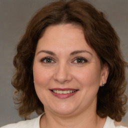 Joyful white adult female with medium  brown hair and green eyes